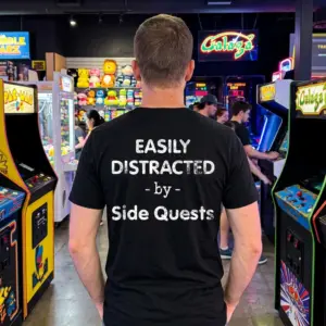 Easily Distracted By Side Quests Funny Gamer T-Shirt 11 Person wearing black T-shirt with 'Easily Distracted by Side Quests' text, outside setting.