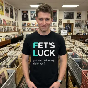 Fets Luck You Read That Wrong T-Shirt 11 Lifestyle shot of a person wearing a black t-shirt with the humorous text 'FET’S LUCK you read that wrong, didn’t you?'.