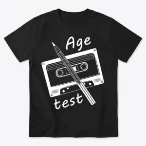 Front flat lay of a black t-shirt featuring a retro cassette tape and pencil graphic with text reading Age test.