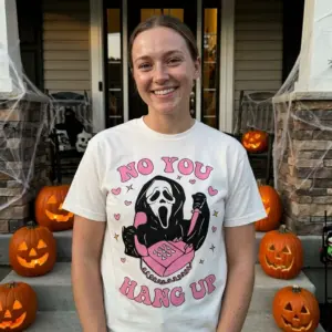 Funny Ghostface No You Hang Up Halloween Tee 10 Ghostface 'NO YOU HANG UP' graphic t-shirt shown in a lifestyle setting, depicting the playful design with pink hearts and stars.