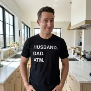 Funny Husband Dad ATM Graphic T-Shirt 10 Lifestyle shot of the 'HUSBAND. DAD. ATM' graphic t-shirt worn in an everyday setting.
