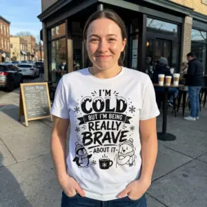 Funny 'I'm Cold But Brave' Winter T-Shirt 10 White shirt with the "I'm Cold But I'm Being Really Brave About It" graphic, including a cute penguin, shivering polar bear, and steaming mug design.