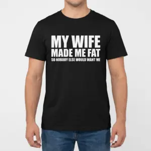 Funny My Wife Made Me Fat T-Shirt 9 Front view of a man modeling a black t-shirt with the humorous quote My Wife Made Me Fat So Nobody Else Would Want Me.