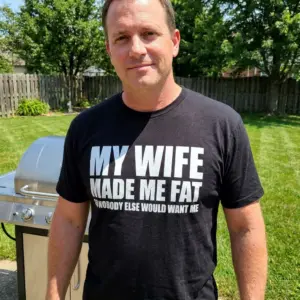 Funny My Wife Made Me Fat T-Shirt 10 Lifestyle view of the black husband graphic shirt with bold text reading My Wife Made Me Fat So Nobody Else Would Want Me.