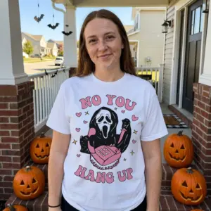 Funny Retro Halloween No You Hang Up Ghostface T-Shirt 10 Lifestyle shot of the white 'No You Hang Up' T-shirt, highlighting the playful Ghostface, pink phone, knife, hearts, and stars design.