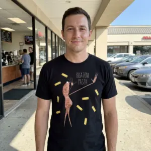 Funny Rigatoni Pasta Surreal Graphic T-Shirt 11 Model wearing a black tee with a rigatoni pasta graphic.