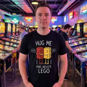 Hug Me and Never Lego Funny Couple T-Shirt 11 Close-up lifestyle view of the playful hugging toy block graphic and 'Hug Me and Never Lego' text on a shirt.