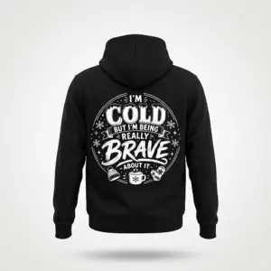 I'm Cold But Really Brave Winter Sarcastic T-Shirt 7 Black hoodie on a flatlay, displaying the white "I'M COLD BUT I'M BEING REALLY BRAVE ABOUT IT" sarcastic winter design with cozy icons on the back.