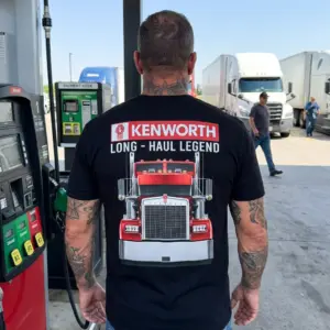 Kenworth Long Haul Legend T-Shirt 10 Person in a T-shirt with Kenworth truck design, outdoors setting.