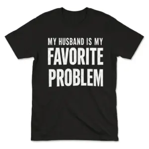 Black t-shirt flat lay with humorous text 'My Husband Is My Favorite Problem'.