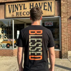 Retro Blessed Vertical Graphic T-Shirt 11 The Blessed Graphic T-Shirt design, seen from the back, with its prominent distressed vertical text in orange and green.