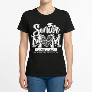 Senior Mom Class of 2027 Funny Graduation T-Shirt 9 Front view of a woman wearing the 'Senior MOM Class of 2027' t-shirt, with a graduation cap and leopard print heart in the design.