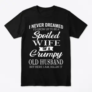 Flatlay of a black T-shirt with humorous white text about a spoiled wife.
