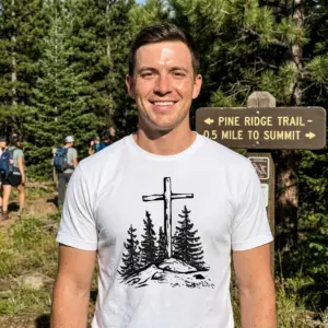 Vintage Christian Cross Pine Trees T-Shirt 11 Person wearing a white t-shirt with a cross and pine trees design.
