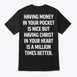 Back flat lay of a black T-shirt reading Having Money In Your Pocket Is Nice But Having Christ In Your Heart Is A Million Times Better.