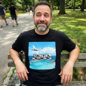 Cartel Network Tropical Island Plane Parody Black T-Shirt 10 Everyday streetwear outfit styling black shirt with black tee front print reading CARTEL NETWORK above a white twin-engine plane over tropical turquoise water