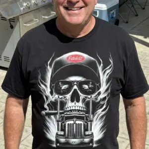 Flaming Skull Trucker Hat Highway Graphic T-Shirt 10 Trucker skull shirt featuring a flaming skull in sunglasses and a trucker hat above a semi truck.