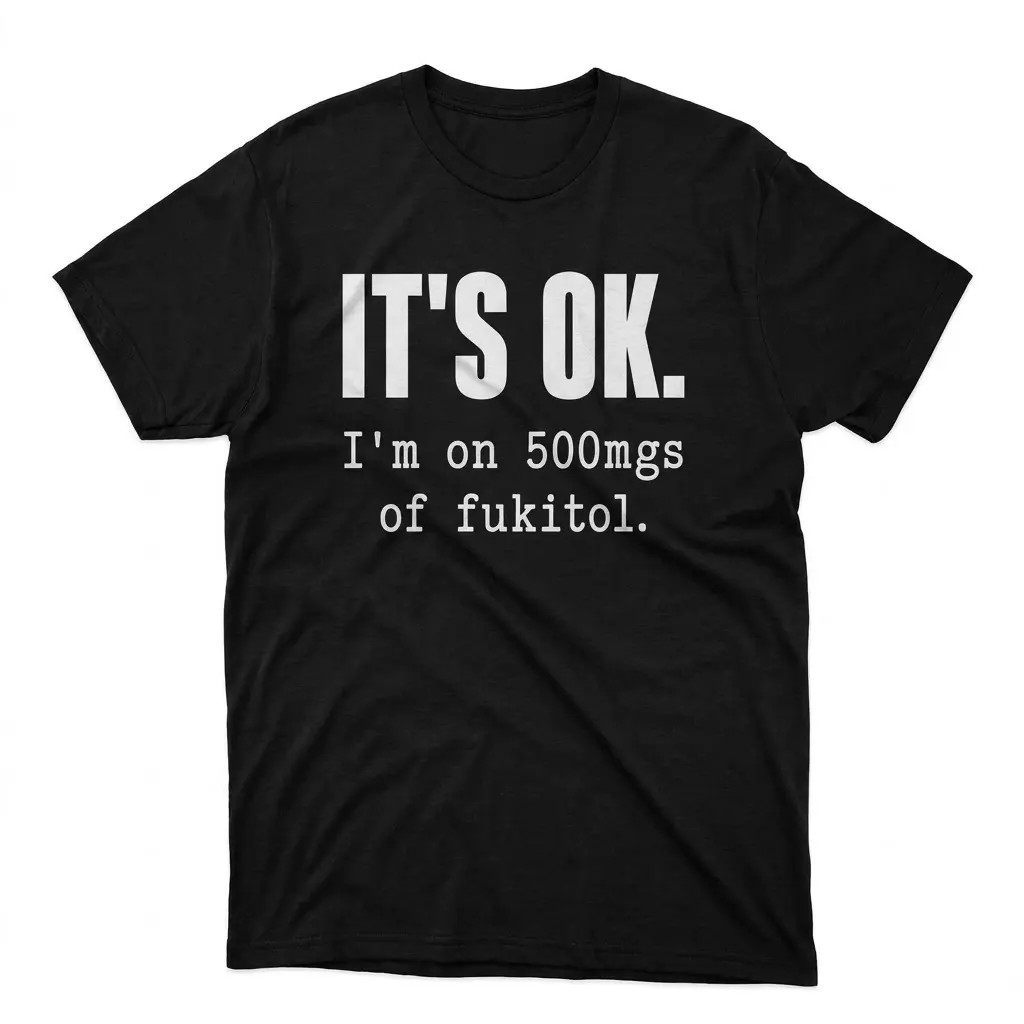 Funny Fukitol Prescription Humor T-Shirt 1 Flat lay of a black t-shirt featuring the humorous text IT'S OK. I'm on 500mgs of fukitol in bold white lettering.