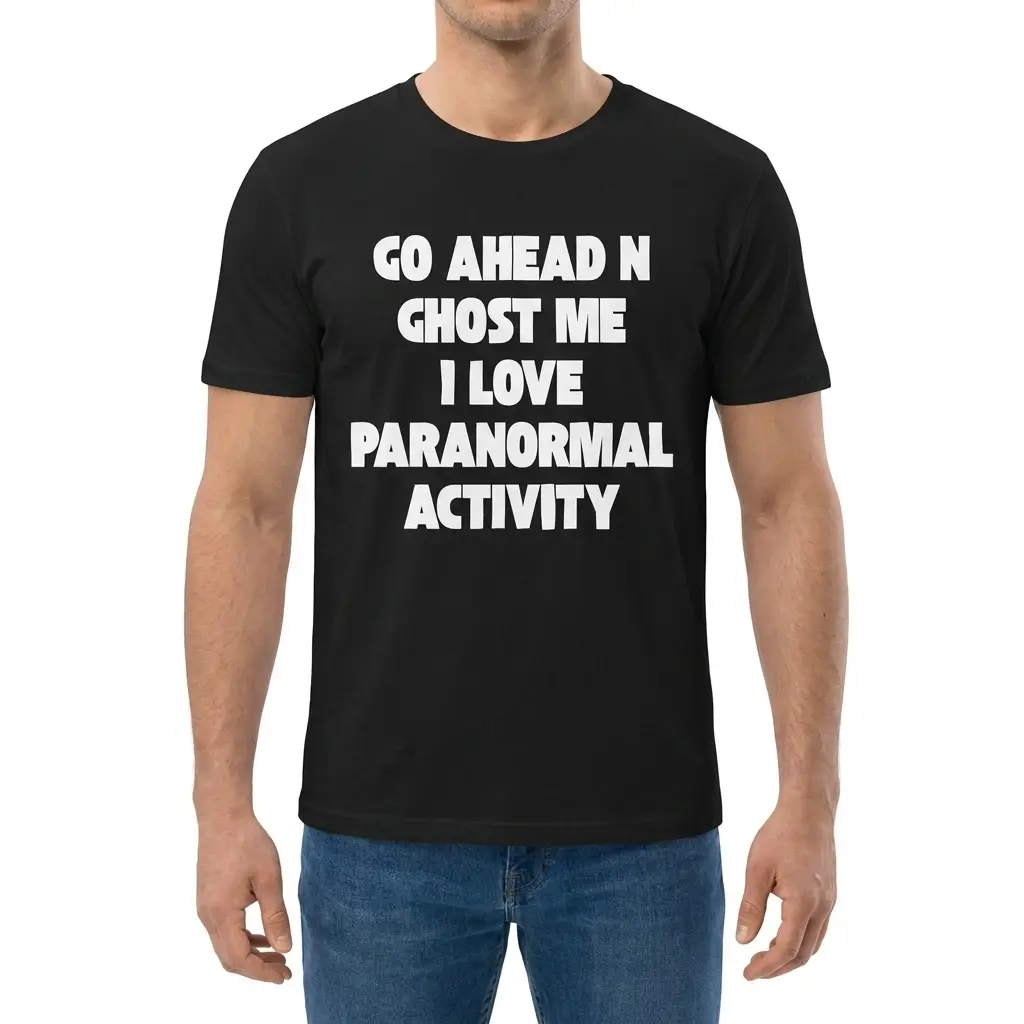 Man wearing black graphic tee with black tee front print reading GO AHEAD N GHOST ME I LOVE PARANORMAL ACTIVITY in bold white letters