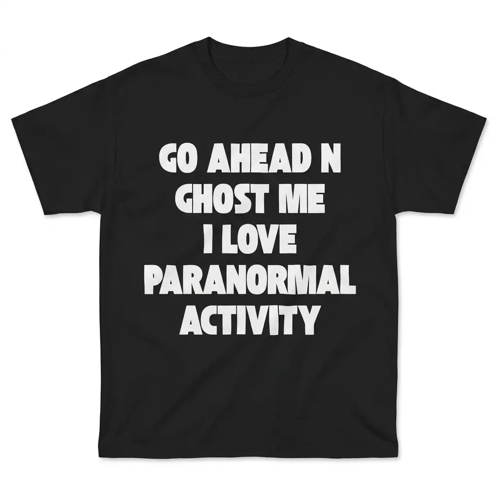 Flatlay black t-shirt featuring black tee front print reading GO AHEAD N GHOST ME I LOVE PARANORMAL ACTIVITY in bold white letters