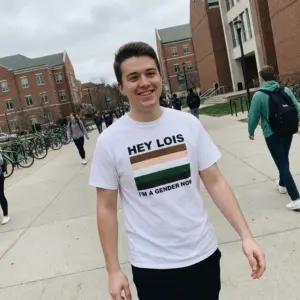 Hey Lois I'm A Gender Now Cartoon Color Flag Meme T-Shirt 10 Everyday streetwear outfit styling white shirt with white tee front print reading HEY LOIS IM A GENDER NOW with a five-stripe cartoon color palette flag