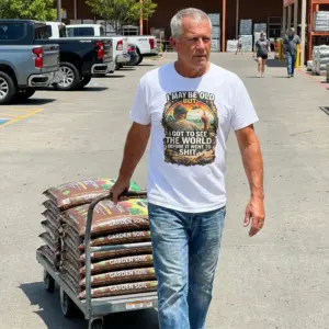 I May Be Old But I Got to See the World Funny Retro T-Shirt 10 Lifestyle view of the retro shirt with a vintage graphic of a traveler, vintage vehicles, and humorous world quote.