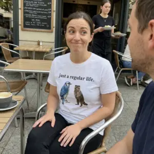 Just A Regular Life Blue Jay And Raccoon Funny White T-Shirt 10 Everyday streetwear outfit styling white shirt with white tee front print reading JUST A REGULAR LIFE above a realistic watercolor blue jay and standing