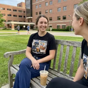 Literally Just An LPN Raccoon Iced Coffee Funny Nurse T-Shirt 10 Everyday streetwear outfit styling black shirt with black tee front print of a raccoon in blue scrubs, LPN cap, sunglasses, and stethoscope drinking iced
