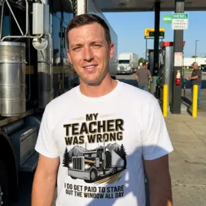 My Teacher Was Wrong I Get Paid To Stare Out The Window Tee 10 Candid photo of a trucker wearing the white My Teacher Was Wrong I Get Paid To Stare Out The Window Tee