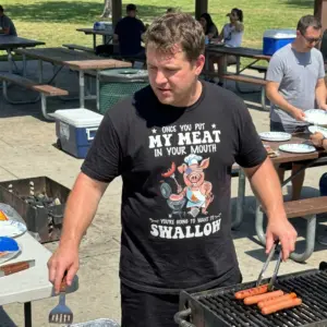 Once You Put My Meat In Your Mouth BBQ Chef T-Shirt 11 Close-up lifestyle view of the funny cartoon pig chef BBQ graphic on a black garment.