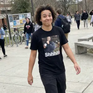 Shhhhh Quiet Street Meme Viral Reaction Graphic Black T-Shirt 11 Close-up casual look showcasing black tee and black tee front print showing the viral Shhhhh street meme photo of a man holding a cup with finger to lips