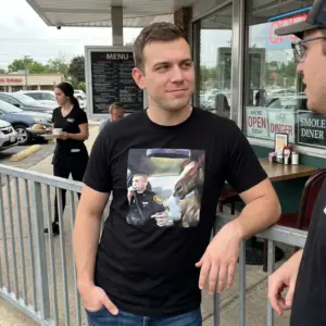 Surreal Officer and Smoking Horse Car Painting T-Shirt 11 Close-up casual look showcasing black tee and black tee front print with a surreal oil painting of an officer and a horse smoking inside a car