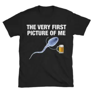 Flat lay of a black t-shirt featuring 'The Very First Picture of Me' text above a sperm cell holding a mug of beer.