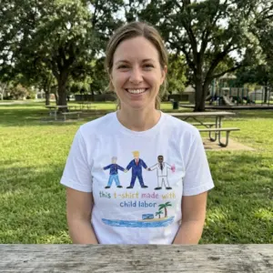 This T-Shirt Made With Child Labor Crayon Satire White T-Shirt 10 Everyday streetwear outfit styling white shirt with white tee front print reading THIS T-SHIRT MADE WITH CHILD LABOR with three crayon figures and a palm