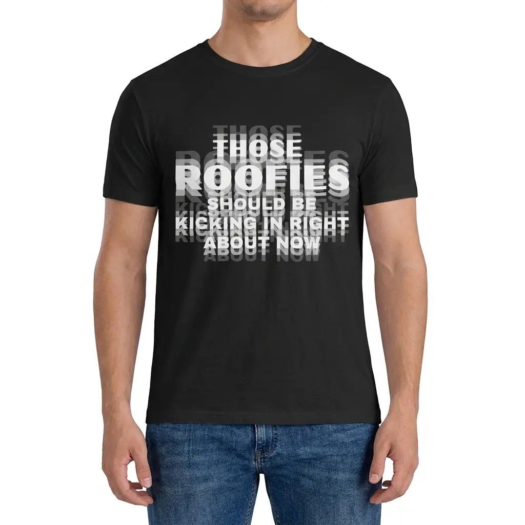 Man wearing black graphic tee with black tee front print reading THOSE ROOFIES SHOULD BE KICKING IN RIGHT ABOUT NOW in blurry layered text