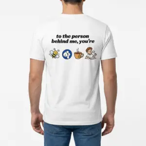 To the Person Behind Me Rebus Puzzle Funny T-Shirt 9 Man wearing white graphic tee with back print reading to the person behind me you're with bee pointing finger tea cup and full cartoon icons