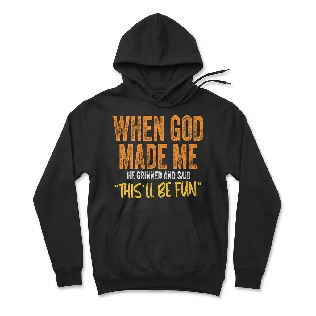 Front flat lay of a black hoodie printed with the funny Christian quote "When God Made Me He Grinned And Said 'This'll Be Fun'".
