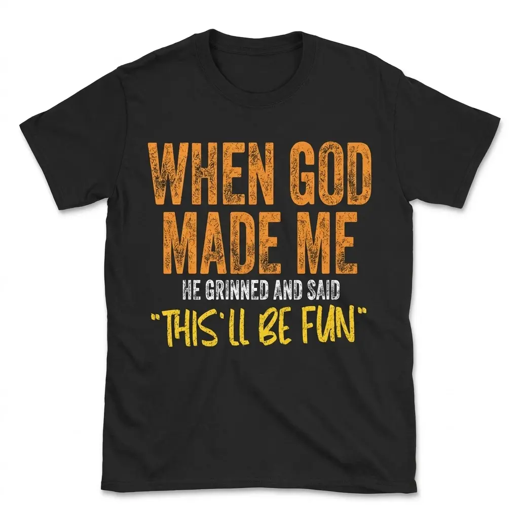 Black t-shirt laid flat featuring distressed text that reads "When God Made Me He Grinned And Said 'This'll Be Fun'".