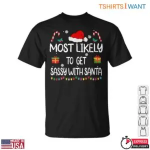 Christmas Items graphic on a black crew-neck t-shirt flat lay reading Most Likely To Get Sassy With Santa with candy canes and gifts.