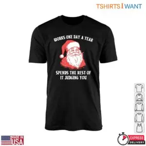 Funny Quotes Santa graphic on a black crew-neck t-shirt flat lay reading Works One Day A Year Spends The Rest Of It Judging You.